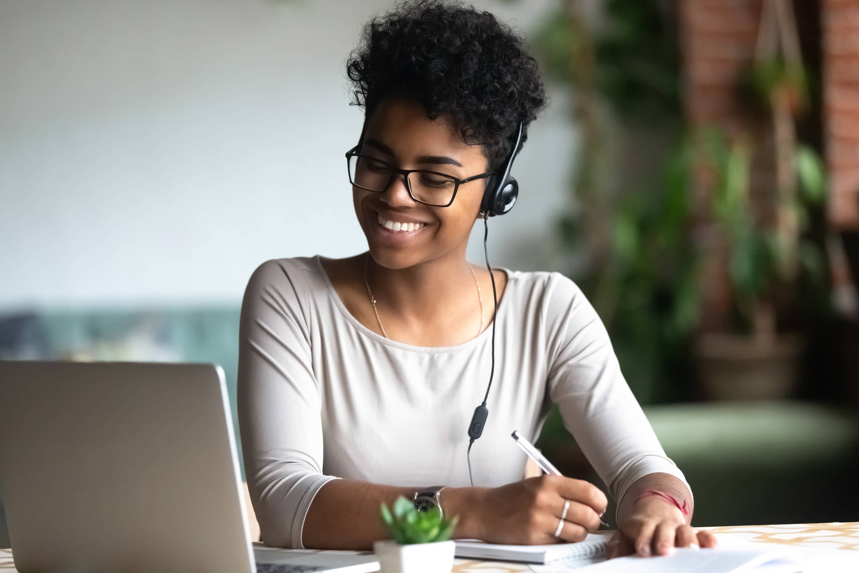 Smiling Biracial Female In Earphones Studying Making Notes