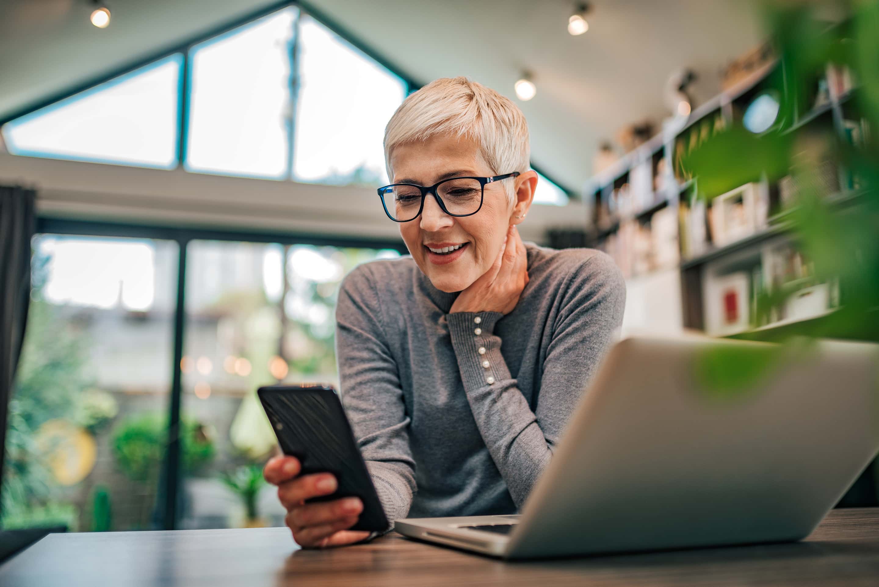 Portrait Of A Cheerful Senior Businesswoman Using Smart Phone At Home Office, Close Up